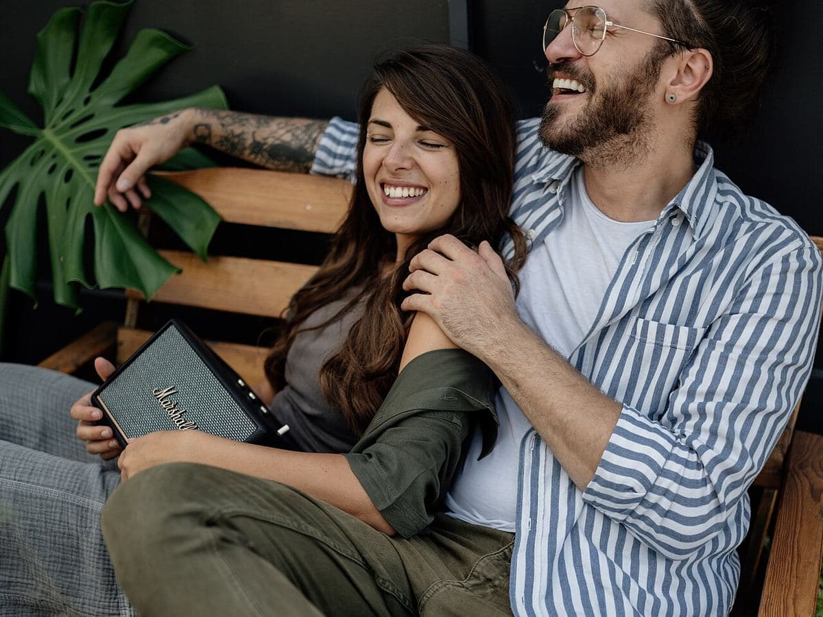 A couple laughing together on a wooden bench